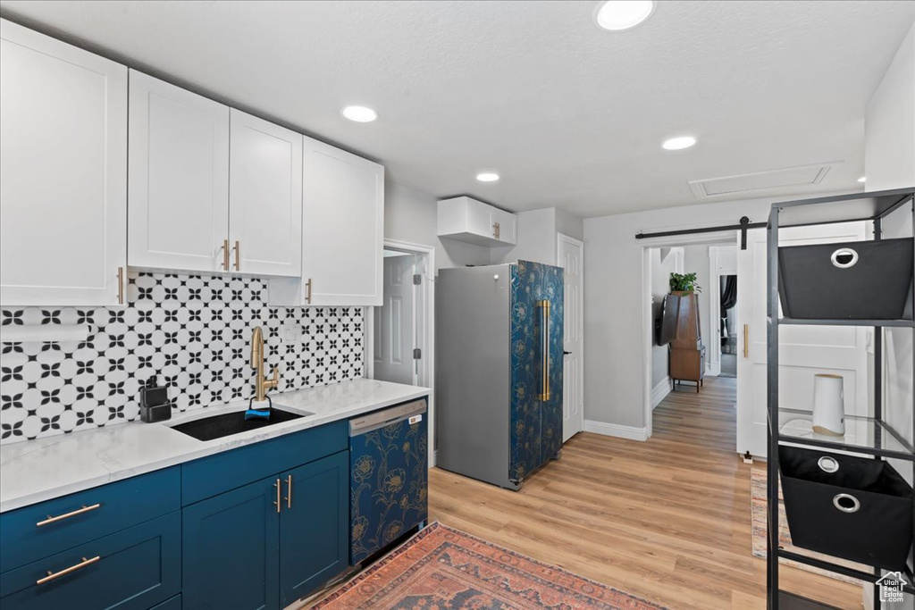 Kitchen with freestanding refrigerator, a sink, blue cabinetry, white cabinetry, and recessed lighting