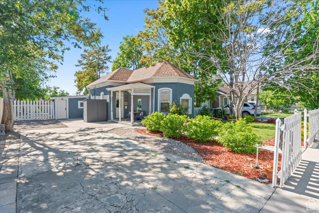 View of front facade featuring stucco siding, fence, driveway, an outbuilding, and a patio area