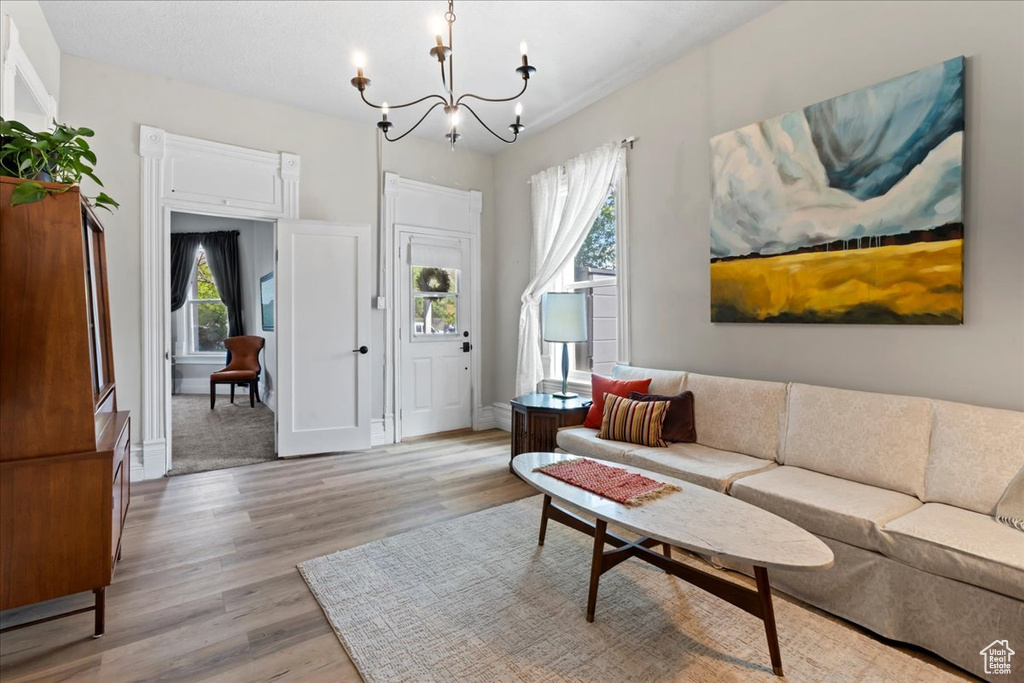 Living area with a chandelier, light wood-style flooring, and baseboards