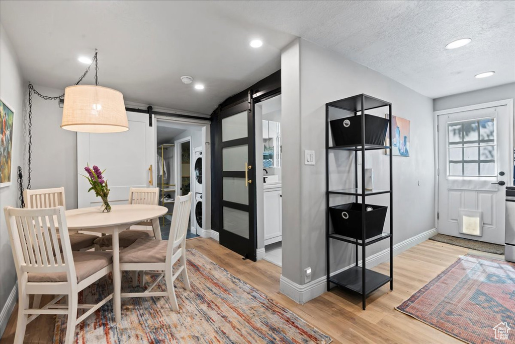 Dining area featuring estacked washer and dryer, a barn door, light wood finished floors, baseboards, and recessed lighting