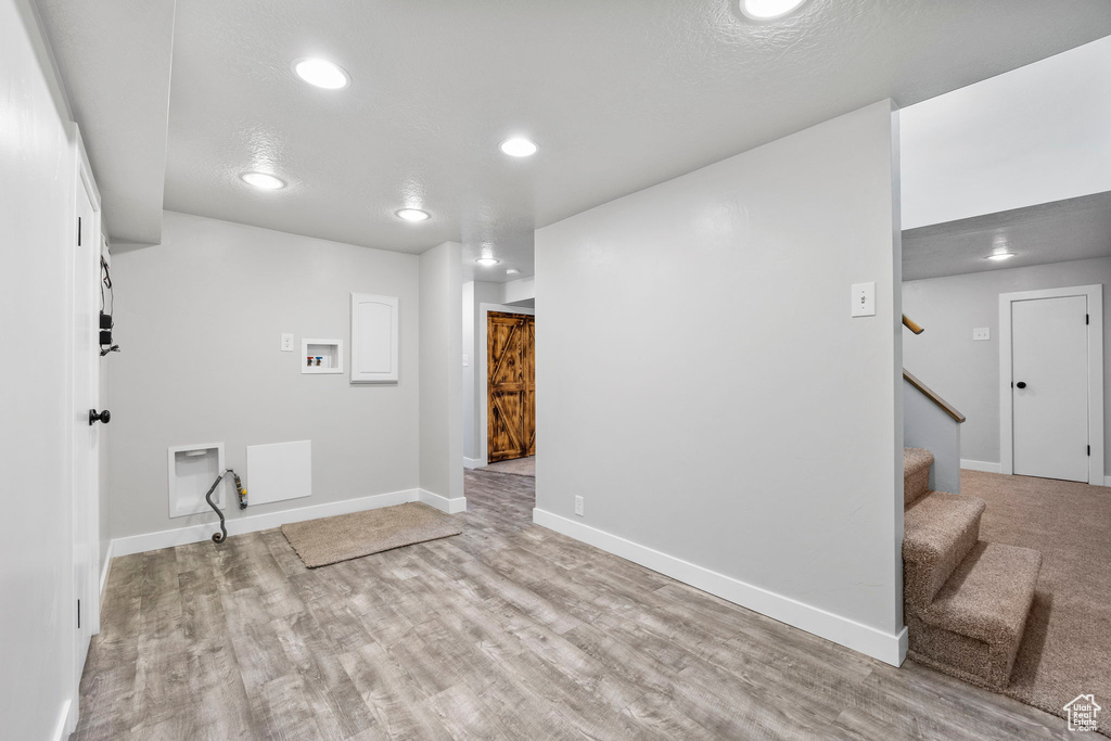 Finished below grade area featuring light wood-style floors, stairway, recessed lighting, and baseboards
