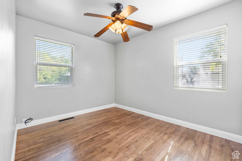 Empty room with baseboards, wood finished floors, and ceiling fan