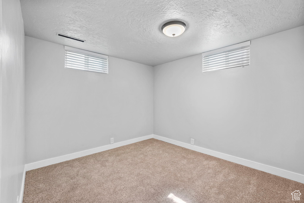Below grade area featuring carpet, a textured ceiling, and baseboards
