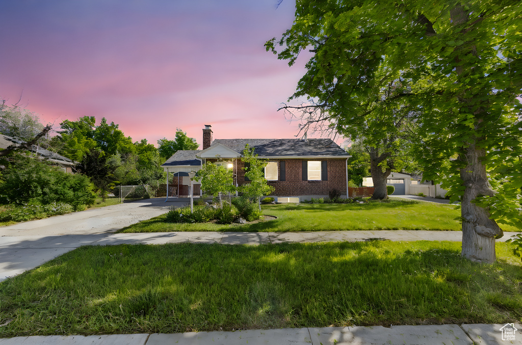 Ranch-style house with a chimney, brick siding, a garage, a front lawn, and concrete driveway