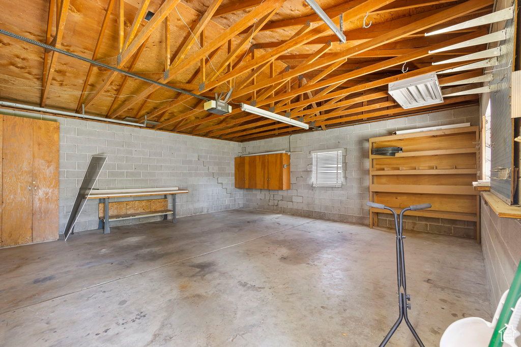 Garage featuring a garage door opener and concrete block wall