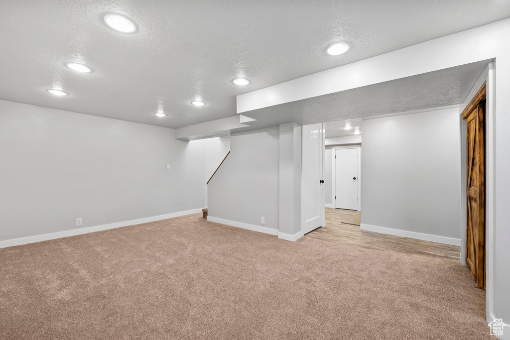 Finished basement featuring light carpet, recessed lighting, a textured ceiling, and baseboards