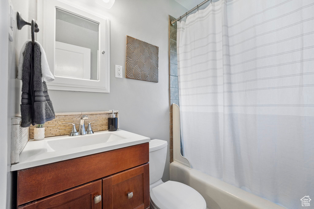 Full bathroom featuring backsplash, toilet, shower / bath combination with curtain, and vanity