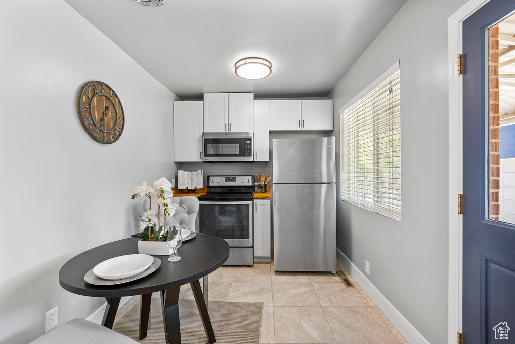 Kitchen with appliances with stainless steel finishes, white cabinetry, and baseboards