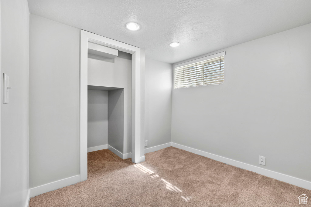 Unfurnished bedroom featuring carpet, a closet, baseboards, a textured ceiling, and recessed lighting