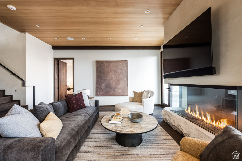 Living room with wooden ceiling, stairs, recessed lighting, wood finished floors, and a glass covered fireplace