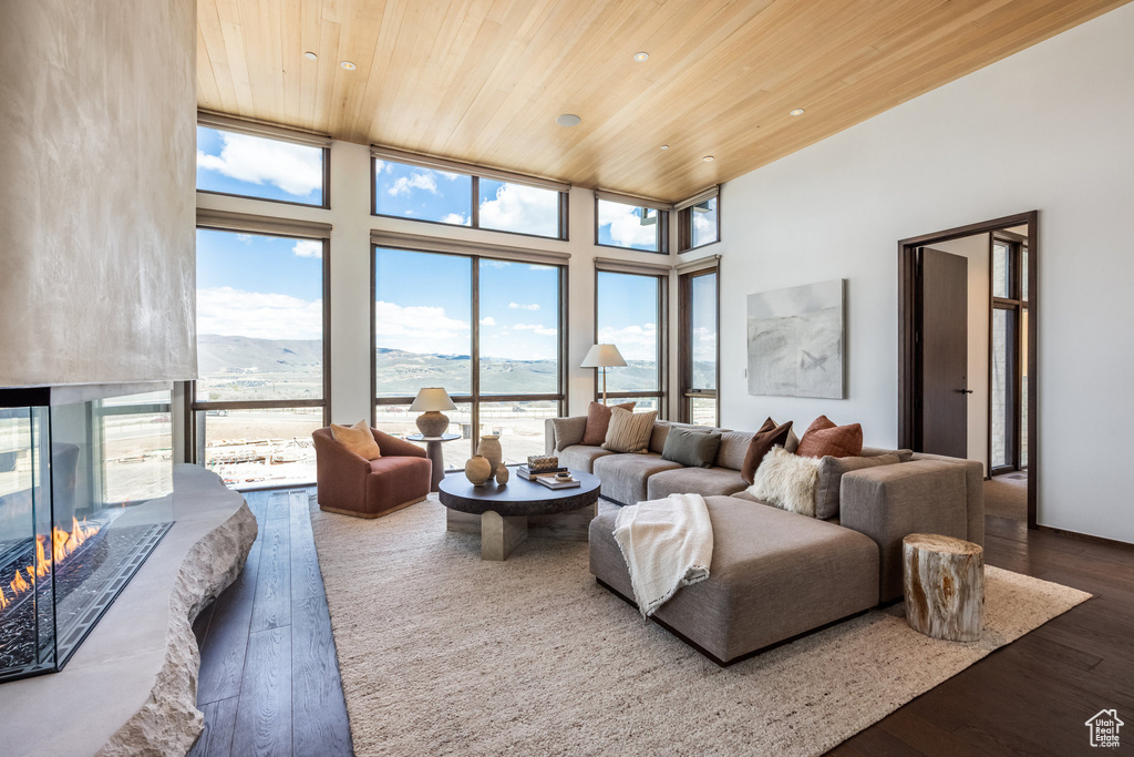 Living area featuring wood ceiling, dark wood finished floors, a mountain view, a multi sided fireplace, and a high ceiling