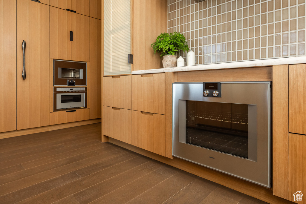 Kitchen featuring oven, beverage cooler, dark wood-style flooring, and light countertops