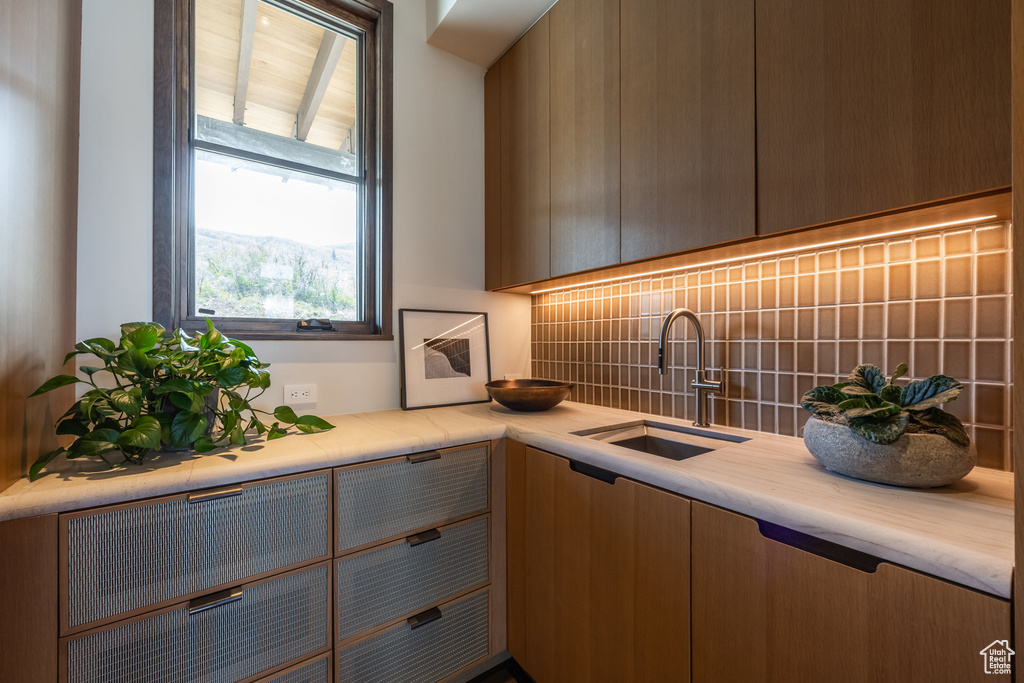 Kitchen featuring a sink, decorative backsplash, and light countertops
