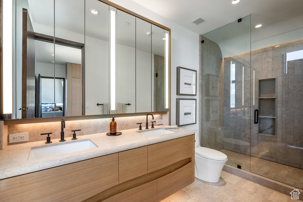 Full bath featuring toilet, a stall shower, double vanity, and recessed lighting