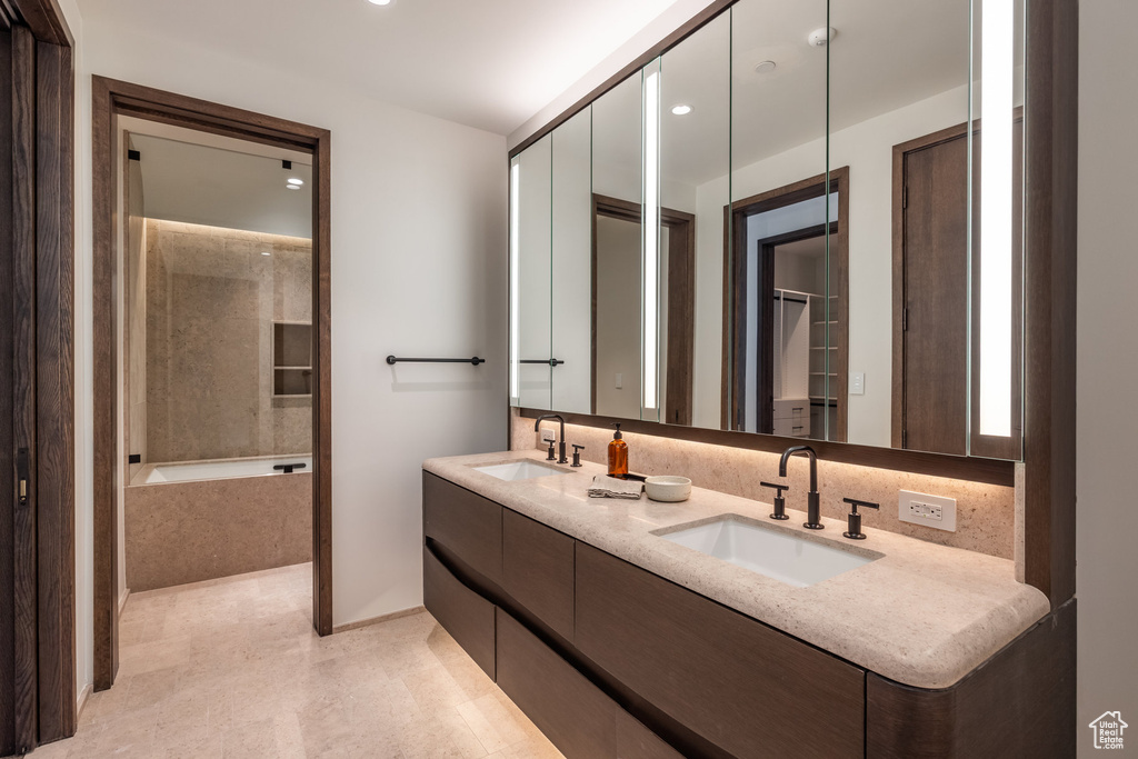 Bathroom featuring a bathtub, double vanity, and recessed lighting