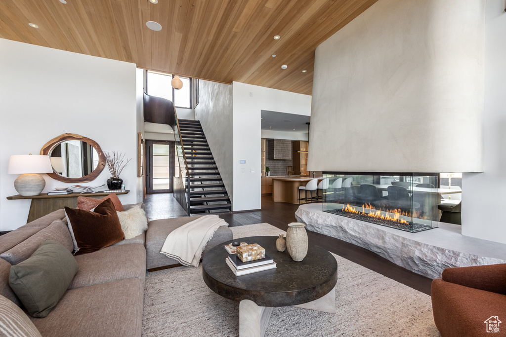 Living room featuring wooden ceiling, recessed lighting, stairway, wood finished floors, and a high ceiling