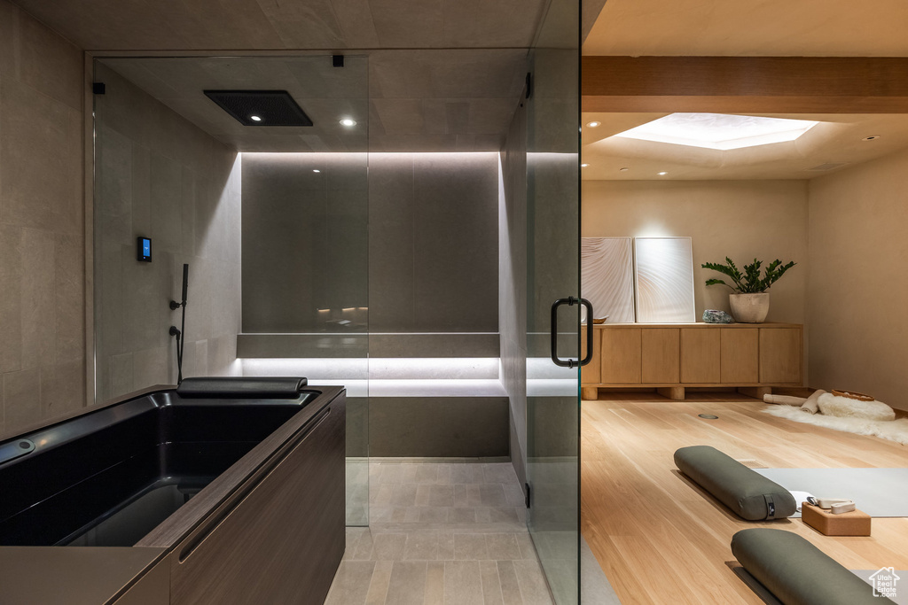 Full bathroom with elevator, a skylight, and a shower with shower door