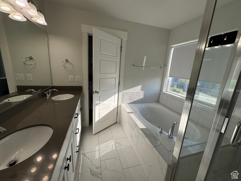 Bathroom featuring marble look tile flooring, a bath, double vanity, and a stall shower