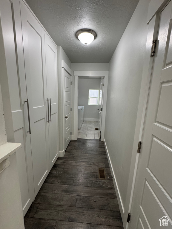 Hallway featuring baseboards, dark wood finished floors, and a textured ceiling