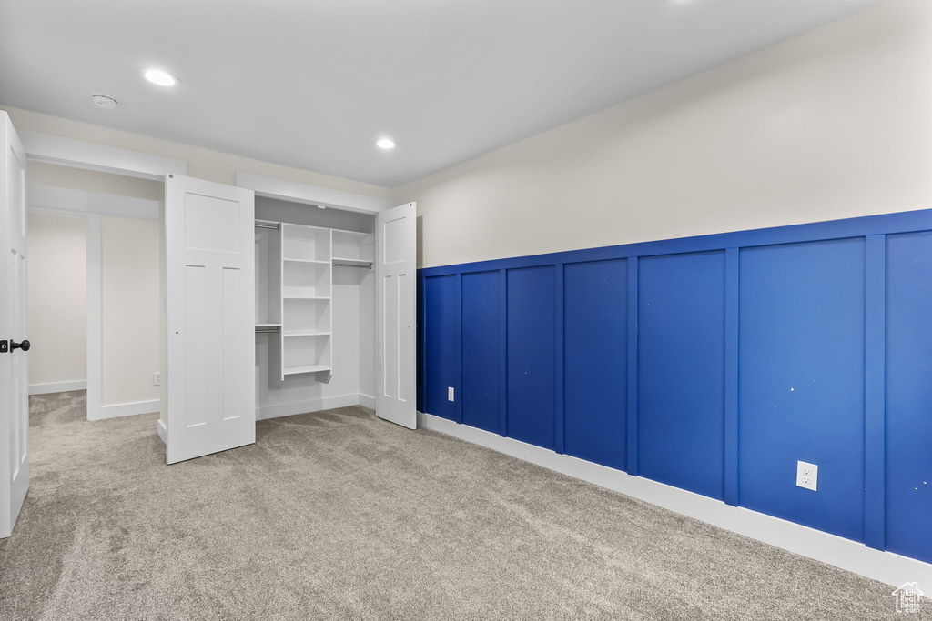 Unfurnished bedroom featuring carpet flooring, a decorative wall, a wainscoted wall, recessed lighting, and a closet