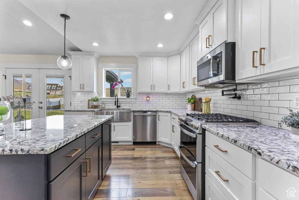 Kitchen with appliances with stainless steel finishes, a sink, white cabinets, and recessed lighting