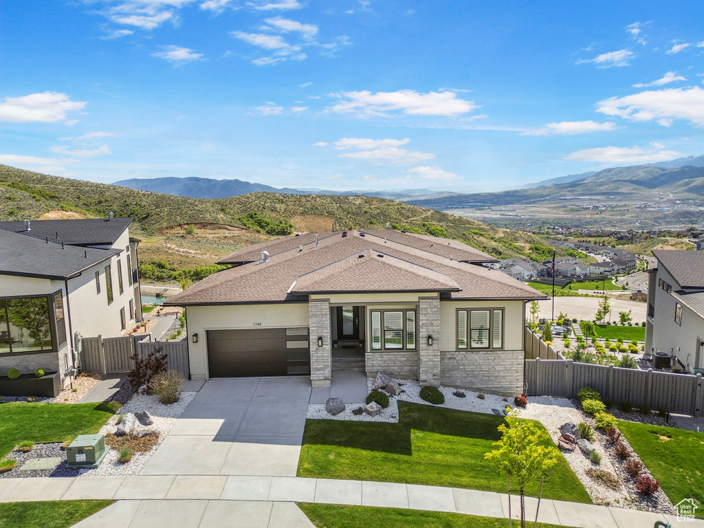 View of front of house featuring a garage, a mountain view, concrete driveway, roof with shingles, and a gate