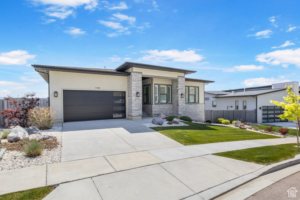 Contemporary house featuring a garage, driveway, and stucco siding