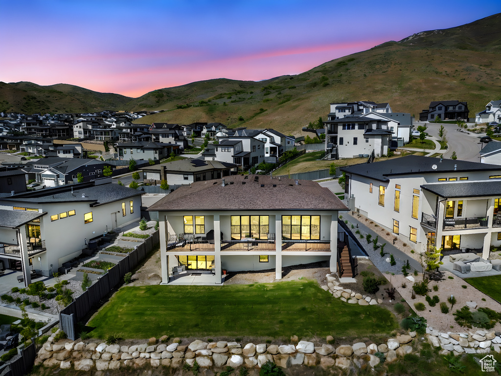 Back of house at dusk with a mountain view, a residential view, and a fenced backyard