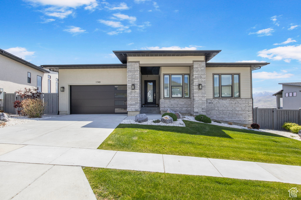 View of front of home featuring a garage, driveway, and stone siding