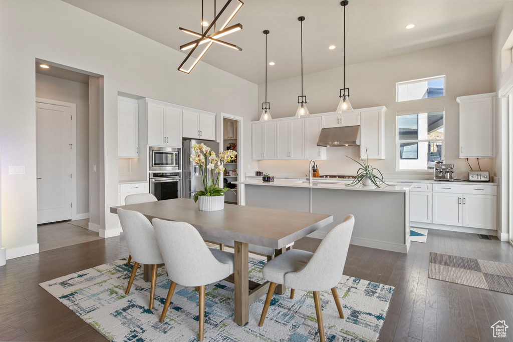 Dining room featuring a towering ceiling, baseboards, dark wood finished floors, recessed lighting, and a chandelier