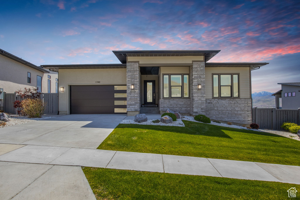 View of front of property with an attached garage, driveway, stone siding, and stucco siding