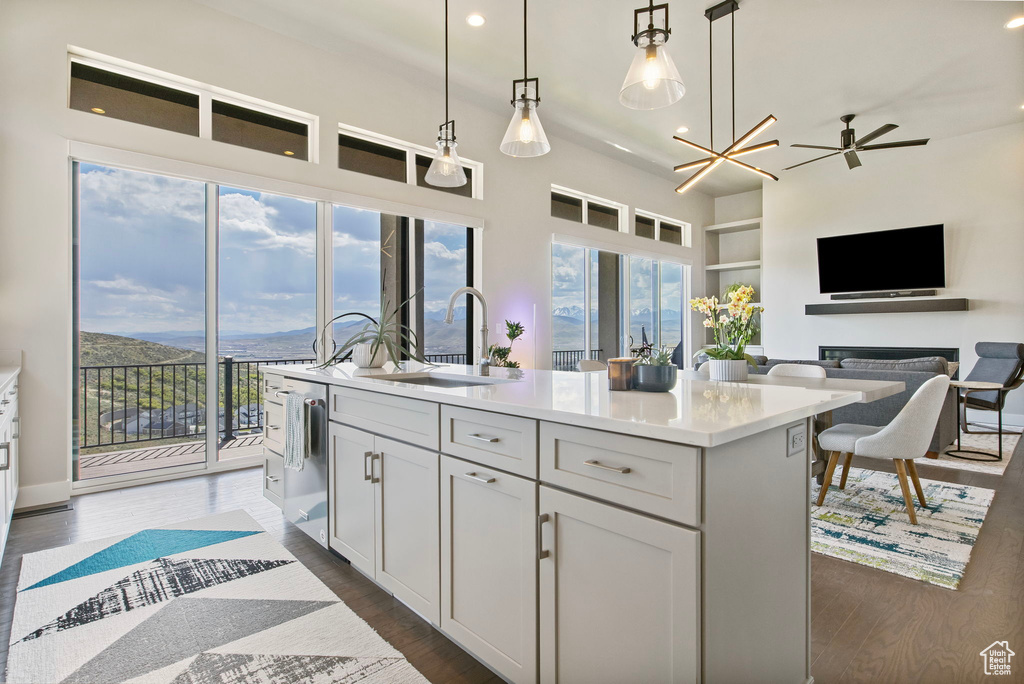 Kitchen featuring a sink, an island with sink, hanging light fixtures, recessed lighting, and light countertops