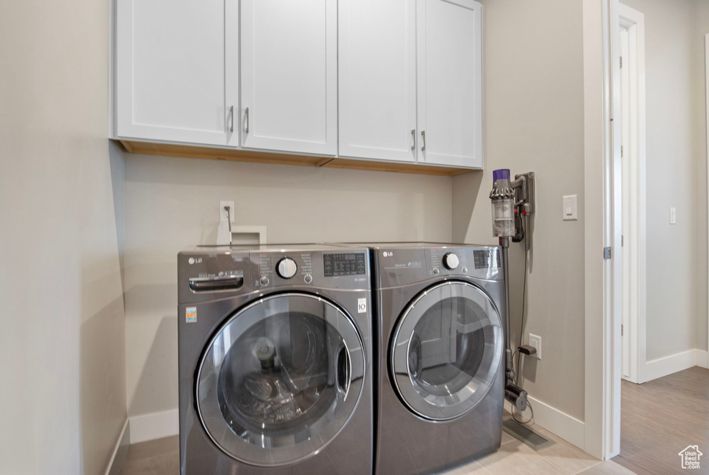 Washroom with cabinet space, washer and clothes dryer, and baseboards