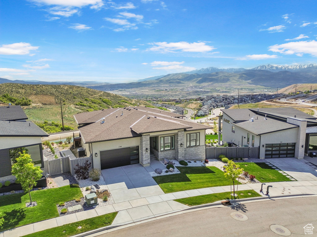 View of front of house with concrete driveway, a mountain view, an attached garage, roof with shingles, and a residential view