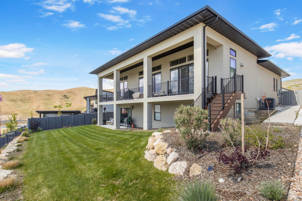Back of property featuring stucco siding, central AC, a balcony, and a mountain view