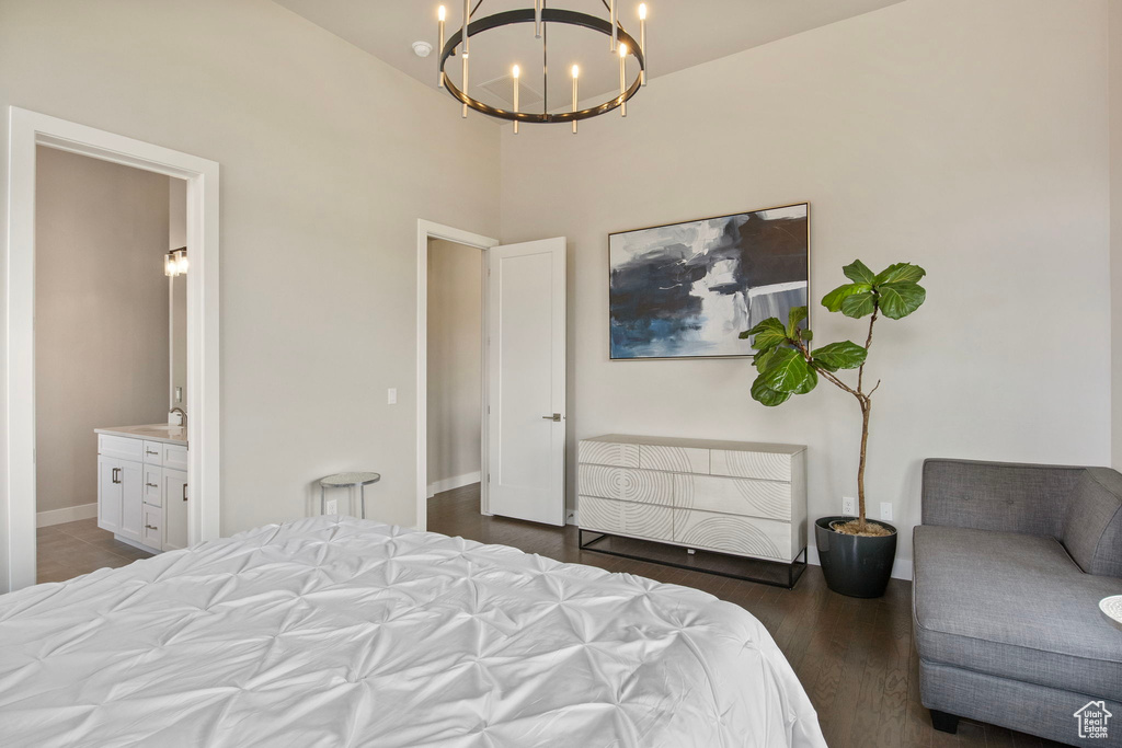 Bedroom featuring a chandelier, baseboards, ensuite bathroom, a sink, and wood finished floors