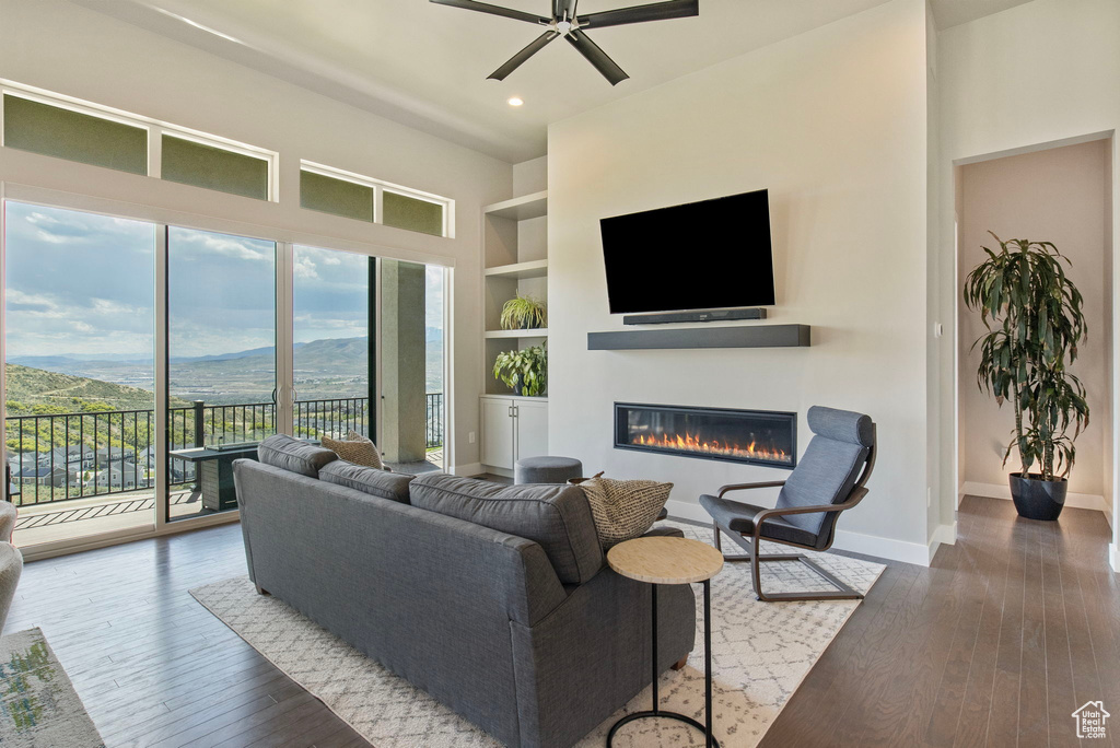 Living area with plenty of natural light, built in shelves, a glass covered fireplace, wood-type flooring, and recessed lighting