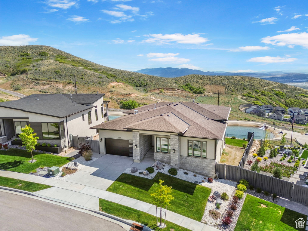 View of front of home with an attached garage, concrete driveway, stone siding, and a mountain view