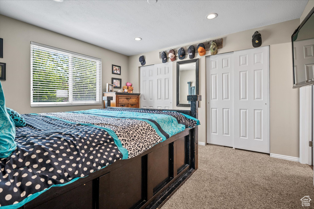 Bedroom featuring two closets, light colored carpet, recessed lighting, baseboards, and a textured ceiling