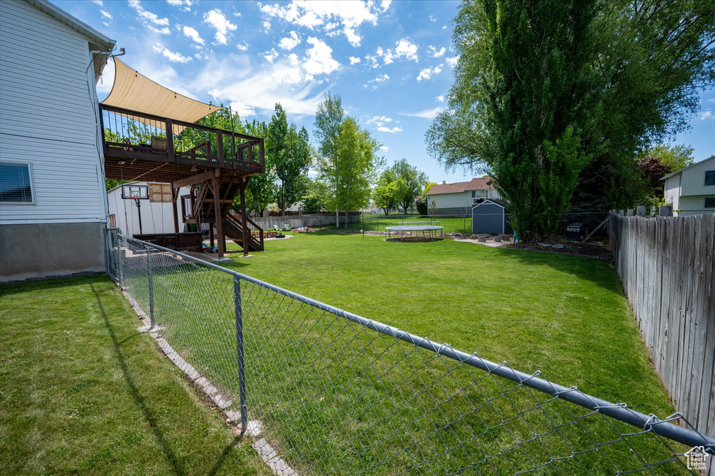 View of yard with a deck, stairs, a shed, and an outbuilding