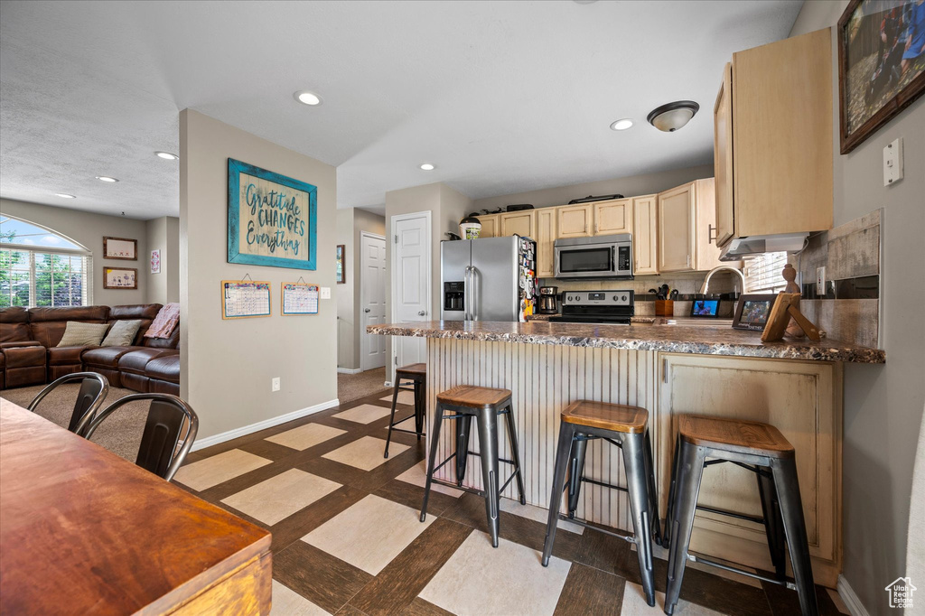 Kitchen with stainless steel appliances, recessed lighting, a peninsula, baseboards, and inlaid floor details