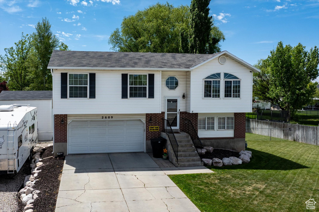 Split foyer home featuring concrete driveway, an attached garage, and brick siding