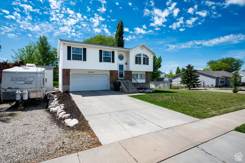 Bi-level home featuring an attached garage, brick siding, and concrete driveway