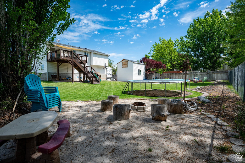 View of patio / terrace featuring a fire pit, a trampoline, stairway, a deck, and an outbuilding