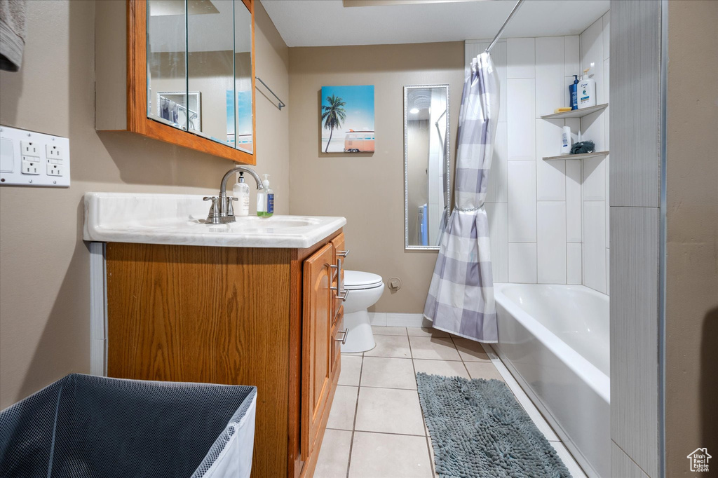 Bathroom with tile patterned flooring, toilet, vanity, shower / bath combo, and baseboards