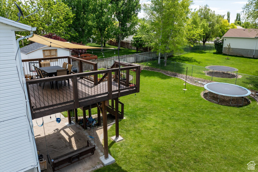 View of yard featuring a trampoline, a deck, and stairs