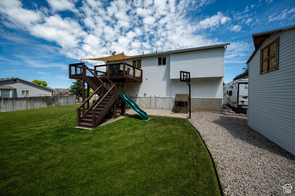 Back of house with a wooden deck, stairs, and a patio area