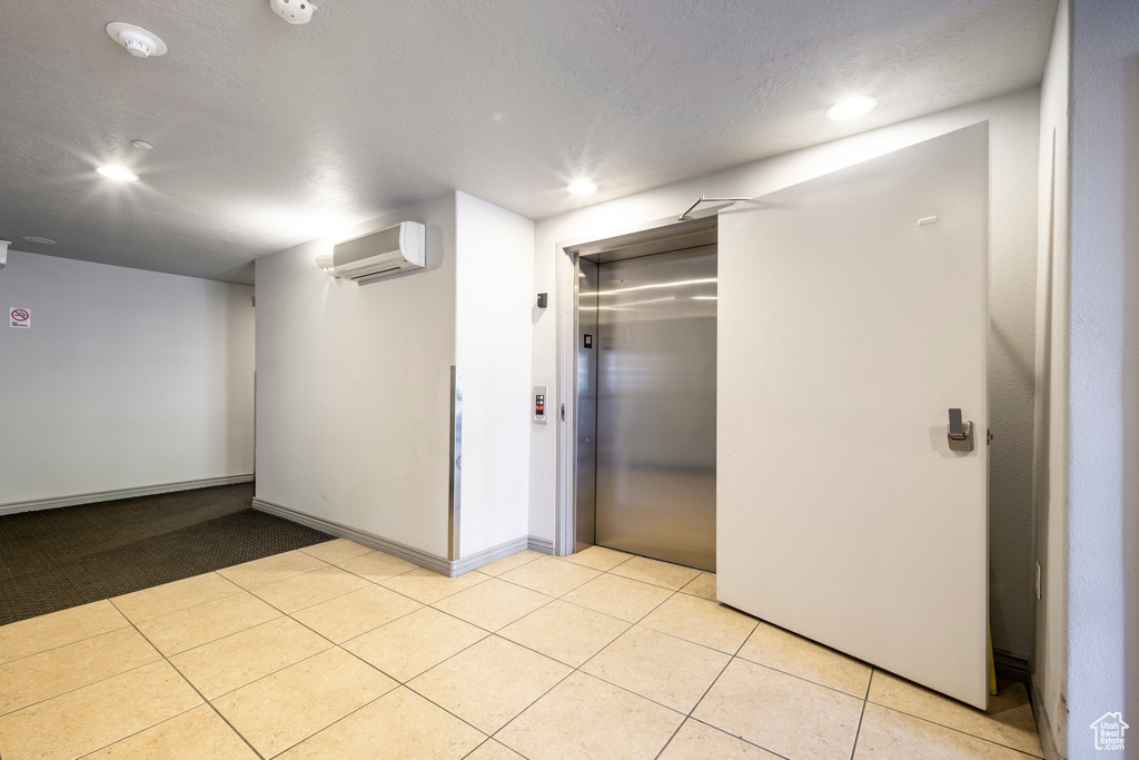Interior space featuring a wall unit AC, elevator, recessed lighting, light tile patterned floors, and baseboards