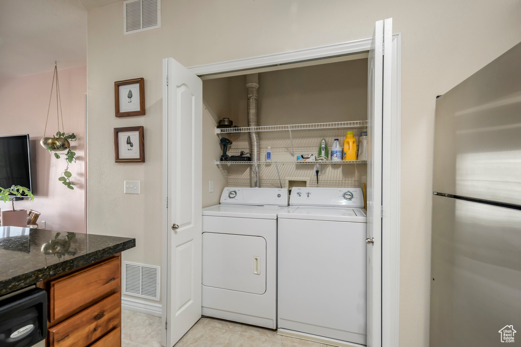Clothes washing area with washing machine and clothes dryer and light tile patterned floors