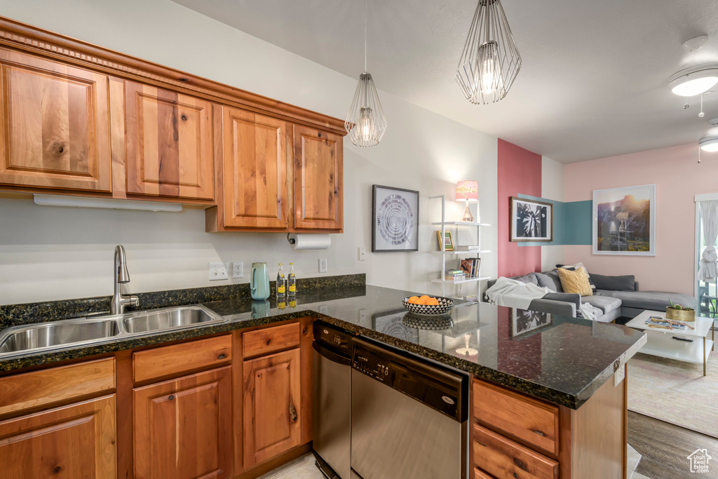 Kitchen featuring stainless steel dishwasher, a peninsula, open floor plan, a sink, and brown cabinets